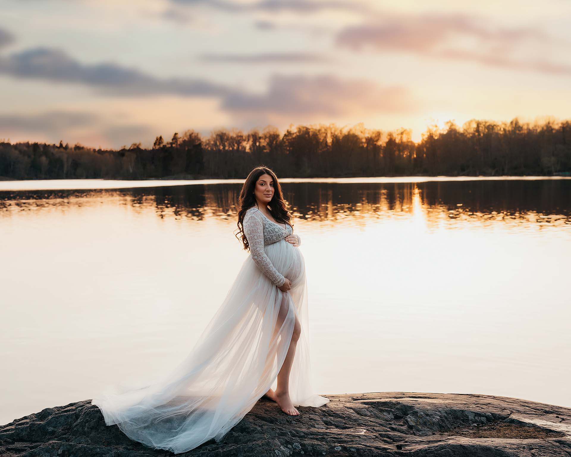 Gravidfotografering utomhus vid havet i Stockholm – gravid kvinna på klippor vid solnedgång