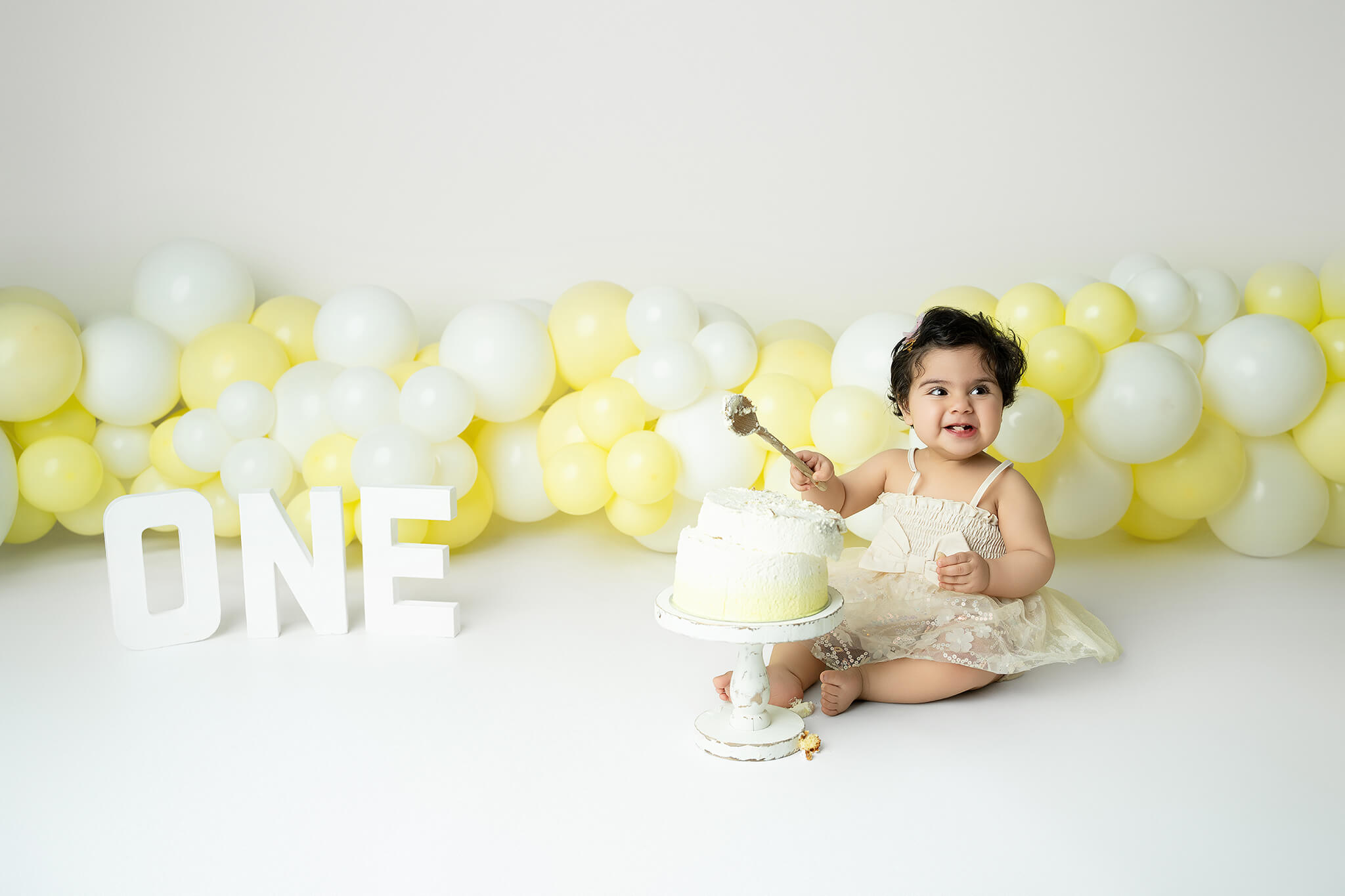 Smash the cake fotografering Stockholm – liten flicka med gul och vit tårta