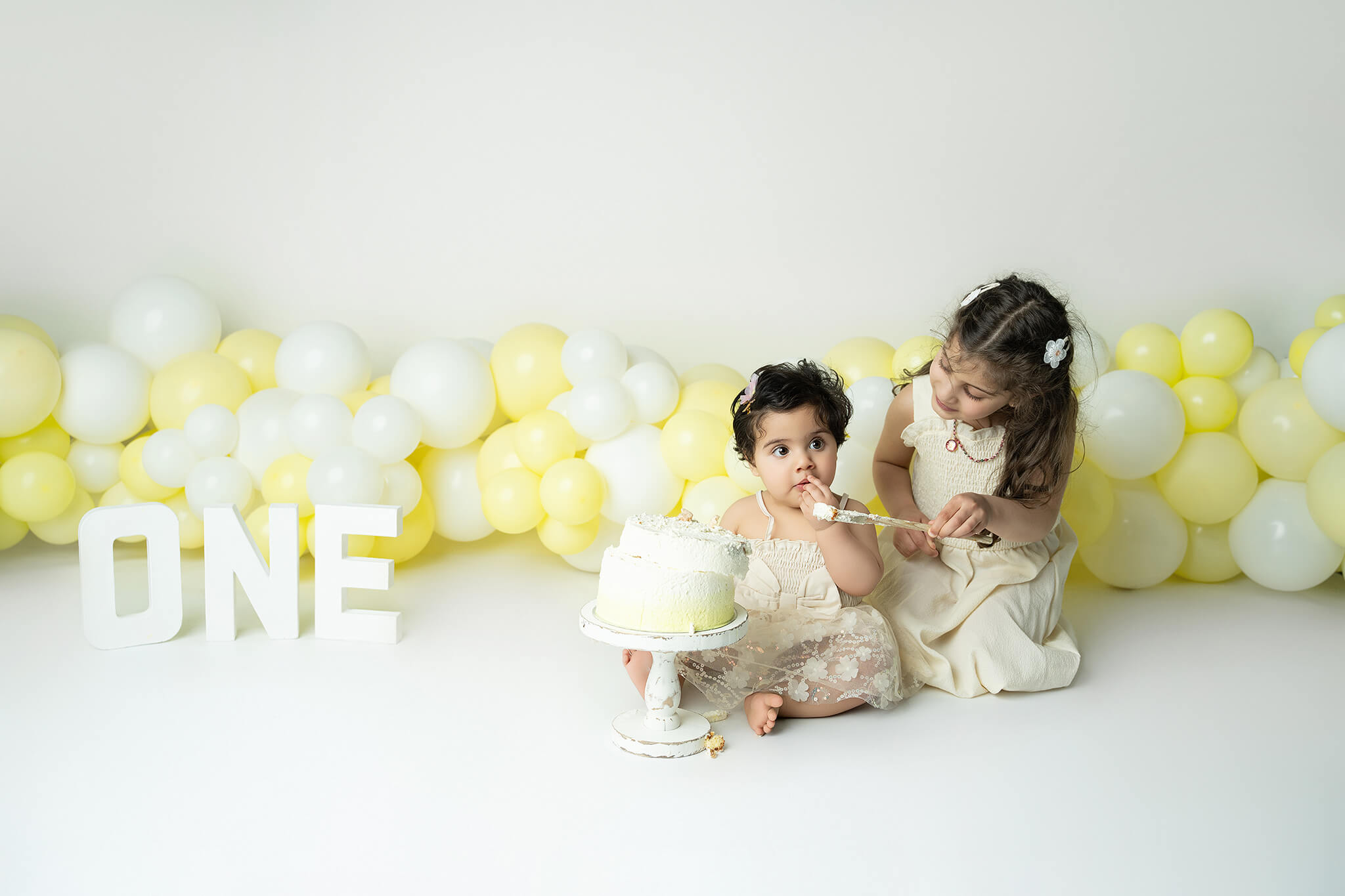 Smash the cake fotografering Stockholm – liten flicka med gul och vit tårta