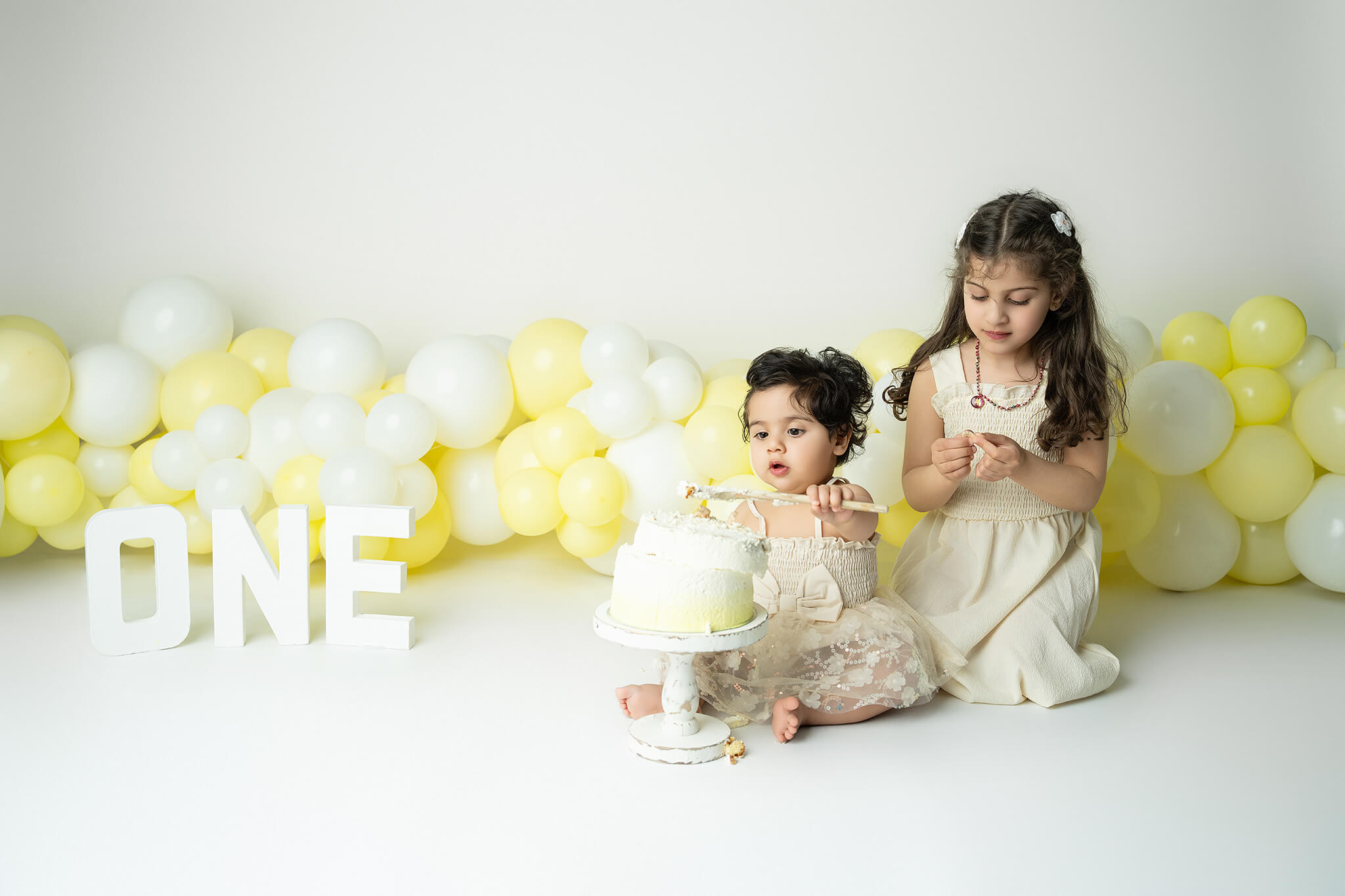 Smash the cake fotografering Stockholm – liten flicka med gul och vit tårta