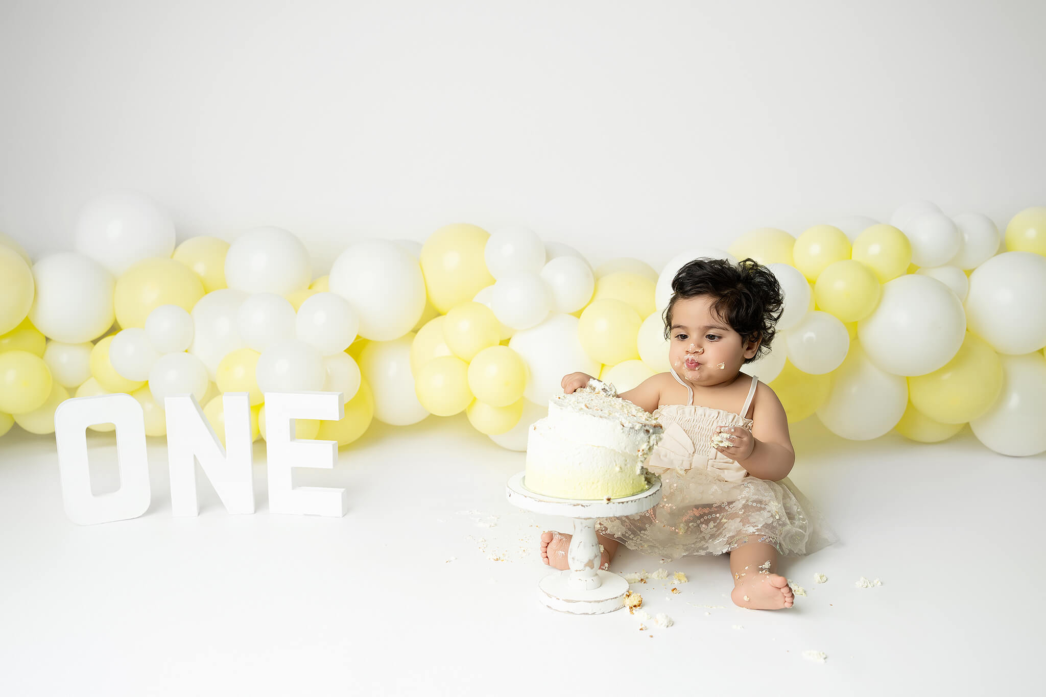 Smash the cake fotografering Stockholm – liten flicka med gul och vit tårta