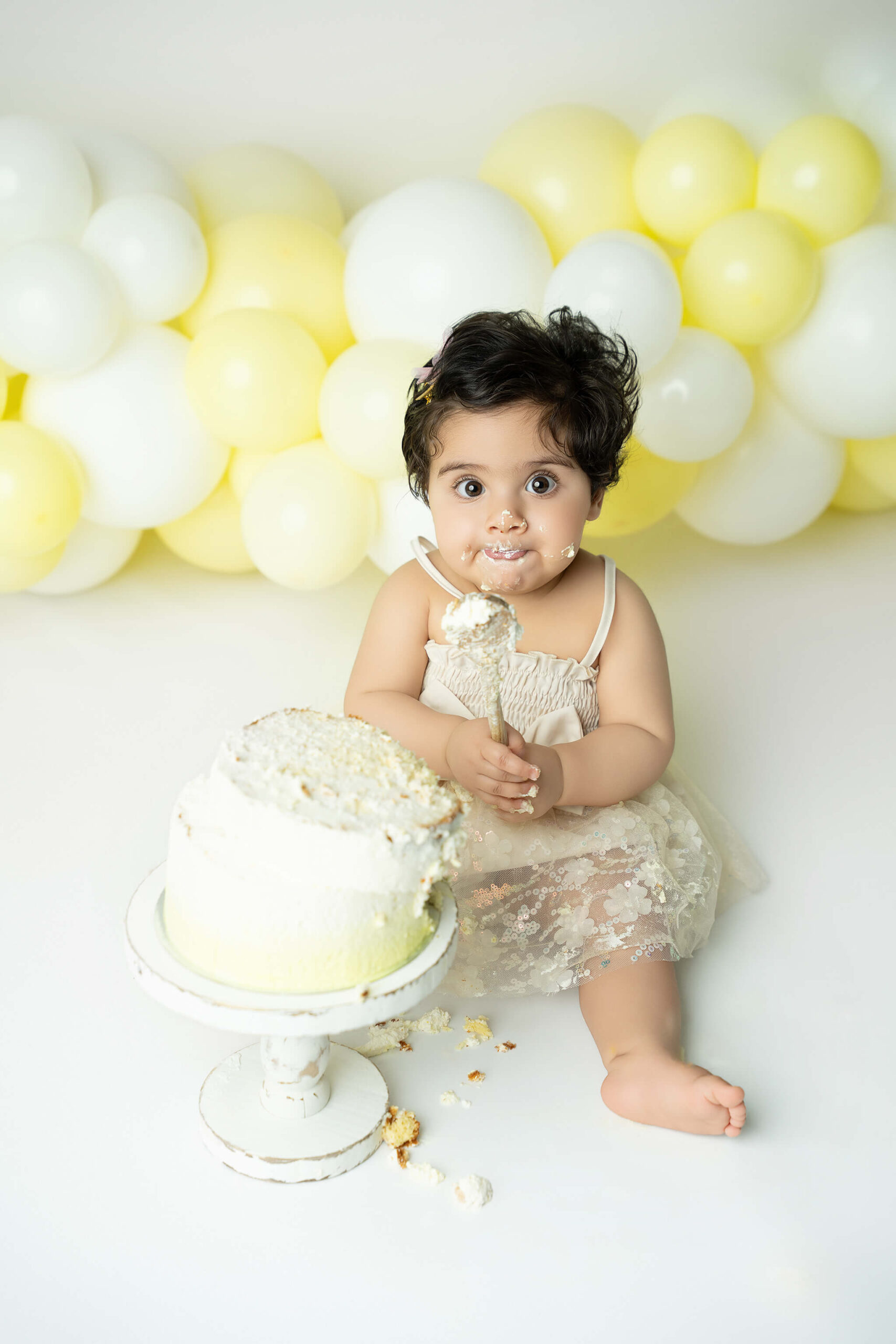 Smash the cake fotografering Stockholm – liten flicka med gul och vit tårta