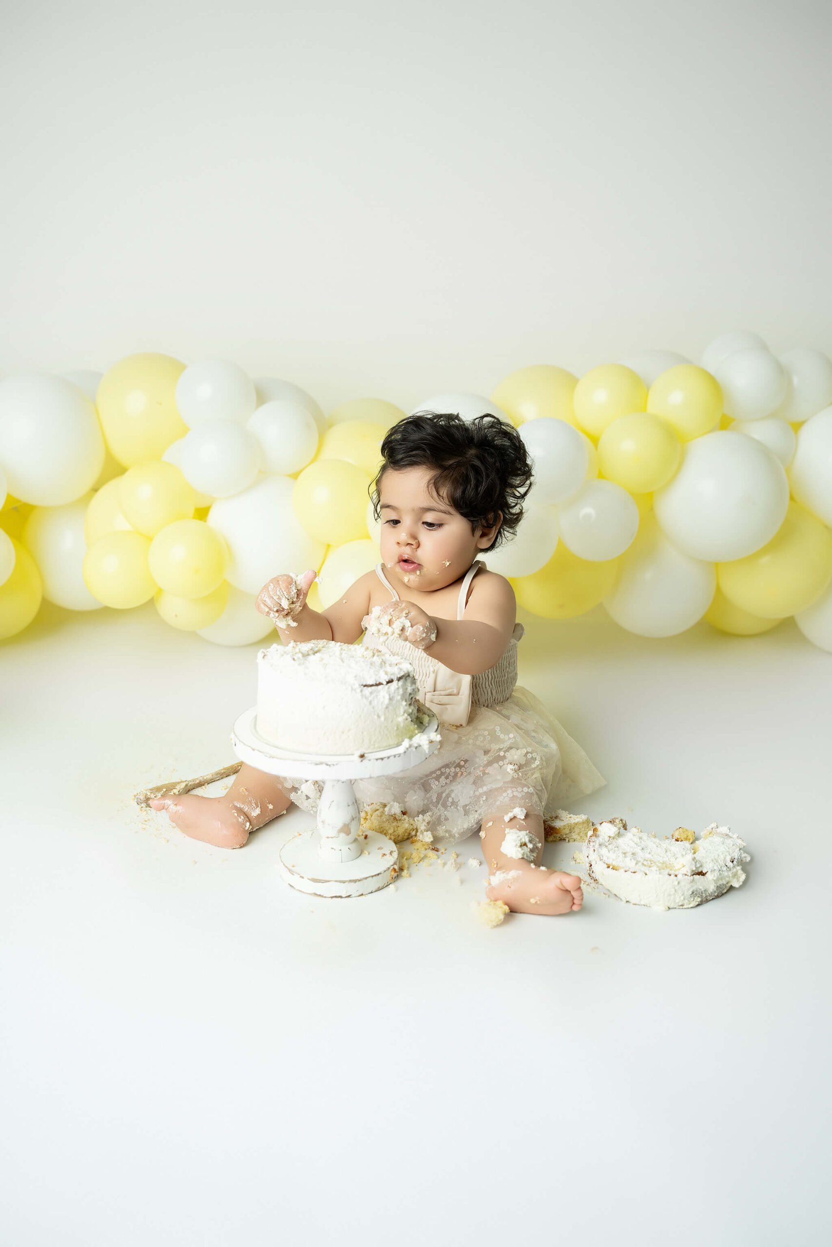 Smash the cake fotografering Stockholm – liten flicka med gul och vit tårta