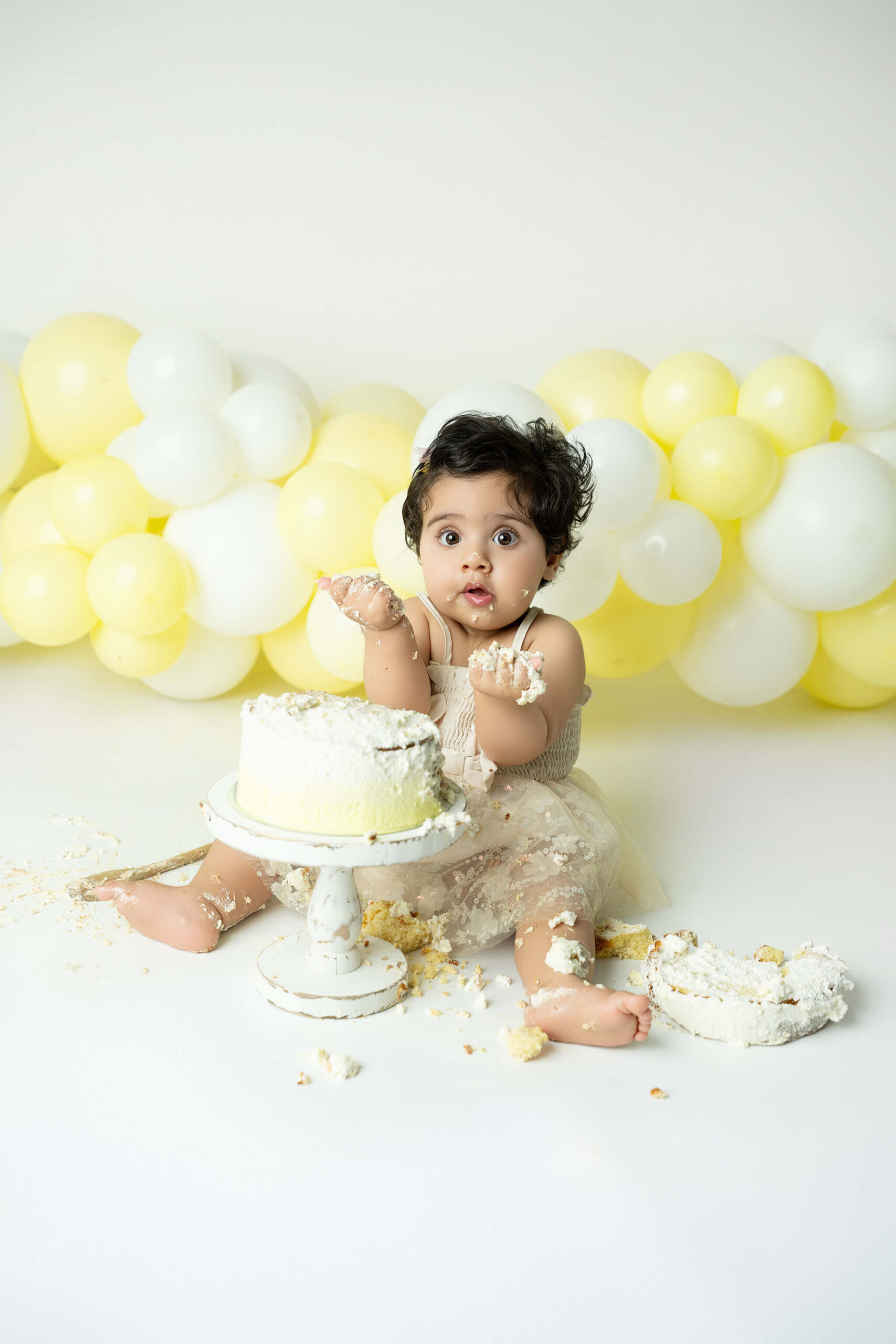 Smash the cake fotografering Stockholm – liten flicka med gul och vit tårta